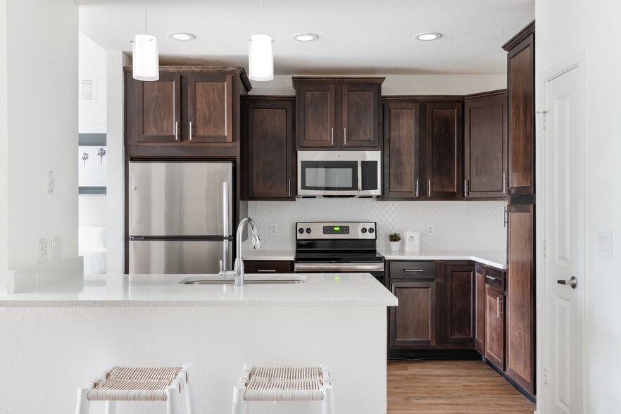Gourmet kitchens feature quartz countertops, stainless-steel appliances, wood cabinetry, and modern designer details - One Boynton
