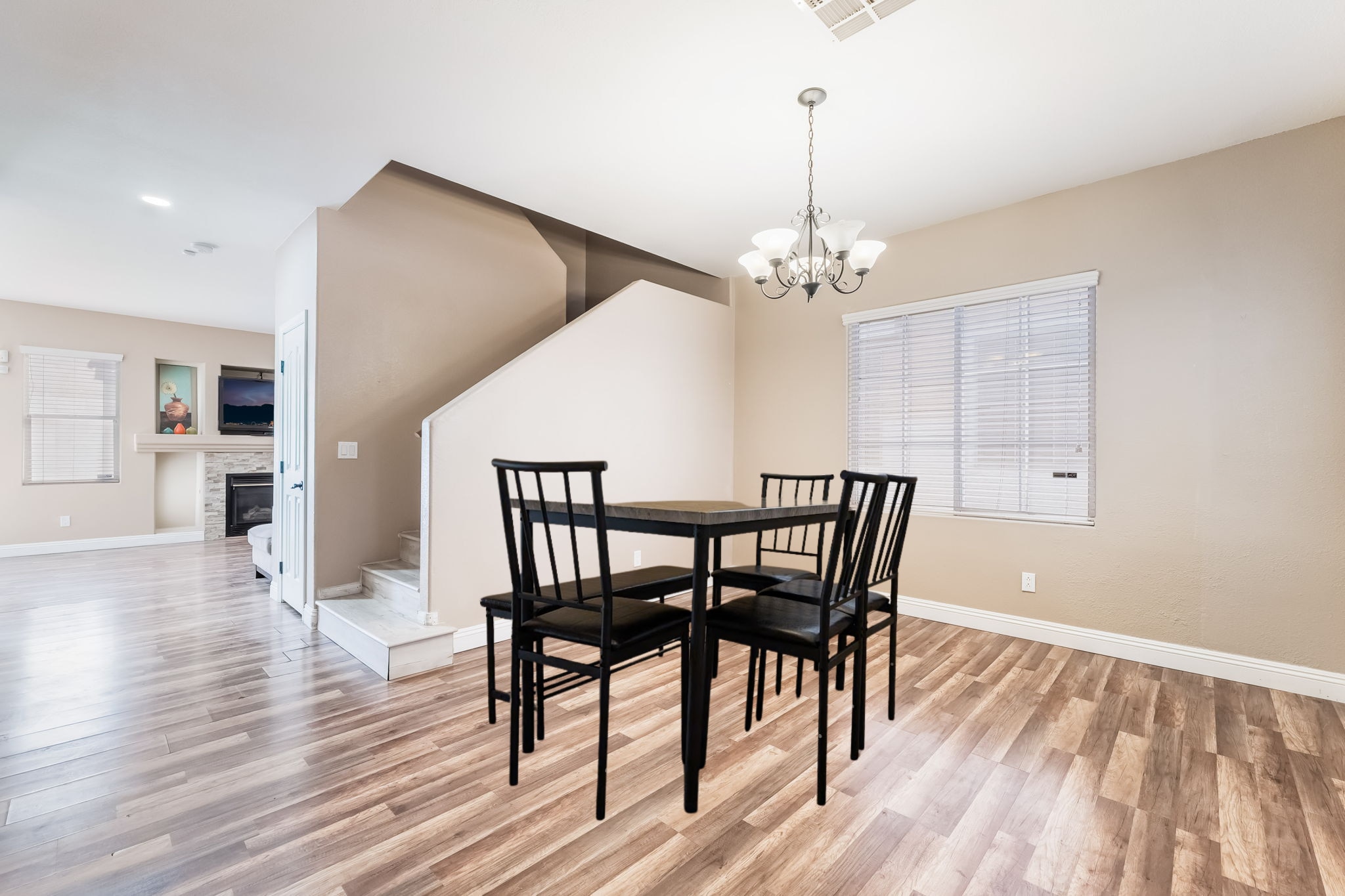 Dining room featuring stairs, light wood-style flooring, a glass covered fireplace, and a chandelier - 1179 Antoinette St