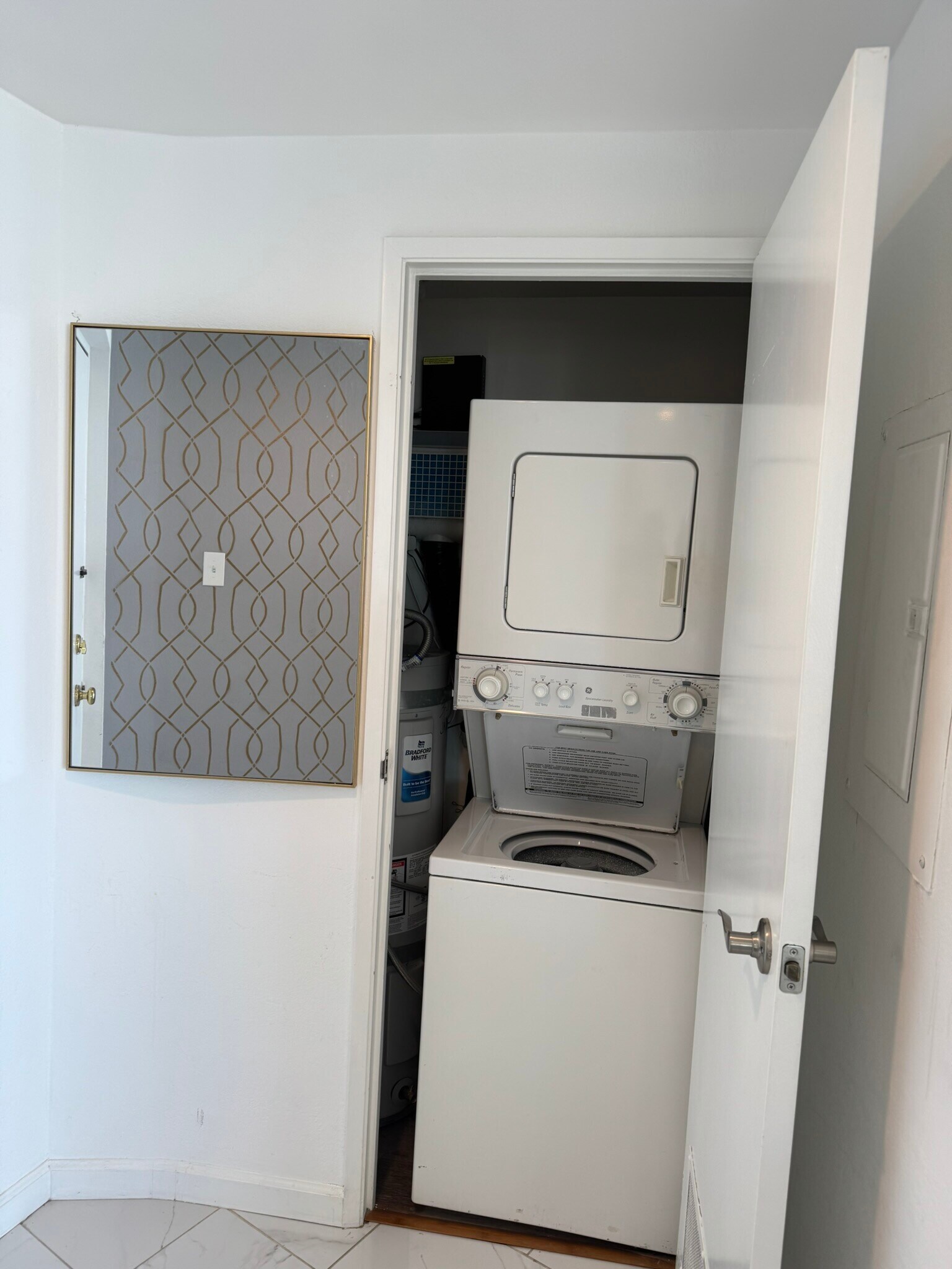 Laundry room closet with stacked washer and dryer along with storage space. - 700 E Ocean Blvd