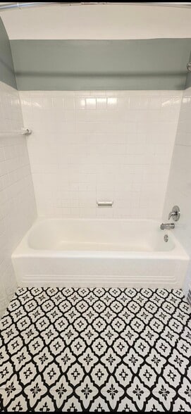 Full bathroom featuring a classic tub/shower combination, timeless wall tile, and striking designer - 90 E 216th St