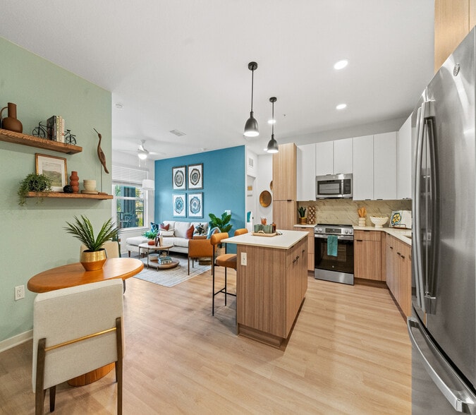 Modern open-concept apartment featuring a stylish kitchen, vibrant living room with accent wall, and elegant decor. - Elan Crown Point
