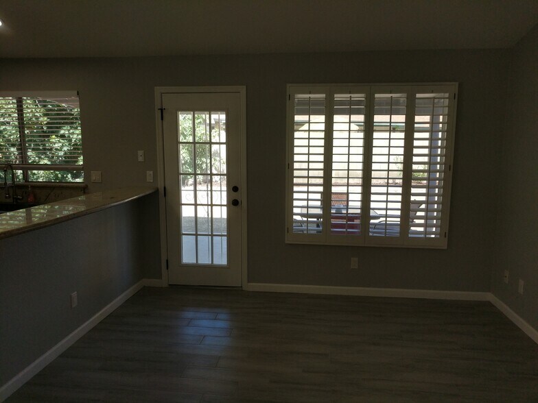 Back patio door, with security door, from Kitchen, next to bar area and wood shudder/blinds. East Wall - 14101 N 78th Dr