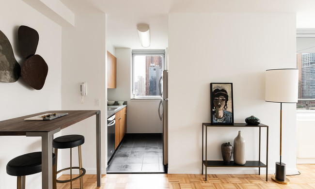 photo of 455 West 37th St Model Apartment 1508 view with foyer and kitchen staged with modern furniture - 455 W 37th St