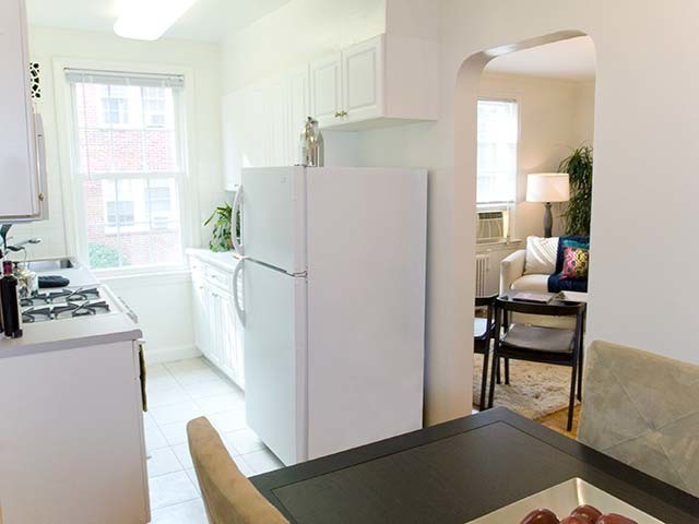 Kitchen and dining area with white appliances, white countertop, white cabinetry and hard surface flooring - eaves Tunlaw Gardens