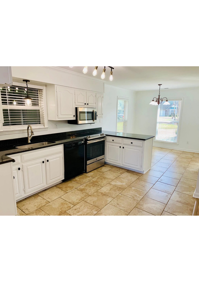 The kitchen is a highlight of the home, featuring white cabinetry with black countertops. - 1602 Bubbling Brook Dr