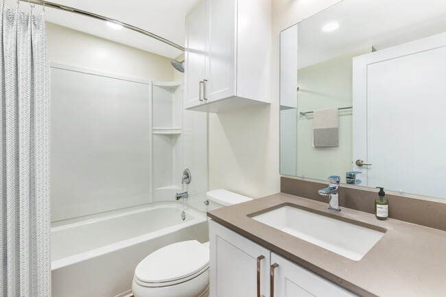 Renovated Package II bath with light grey quartz countertop, white shaker cabinetry, and hard surface flooring - eaves Thousand Oaks