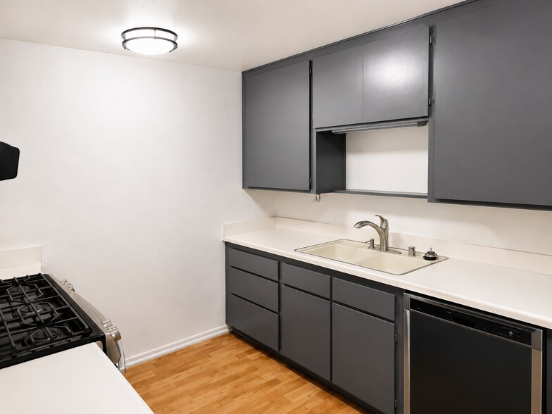 Clean kitchen with gray cabinetry, light countertops, wood-look flooring, and included appliances. - 339 E Taft Ave
