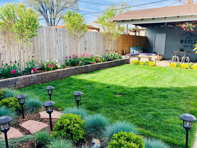 Picturesque garden with lush grass, raised garden bed with annual plants, bulbs, and 3 flowering lil - 1447 Osceola St