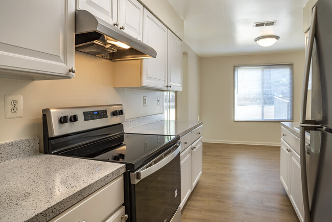 Renovated Package I kitchen featuring stainless steel appliances, white cabinetry, grey laminated countertops, and hard surface flooring - eaves Tysons Corner