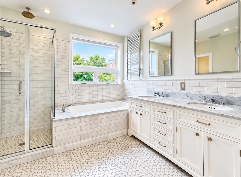 Renovated 3rd floor primary bathroom with double vanity, soaking tub and glass enclosed shower - 2322 1st St NW