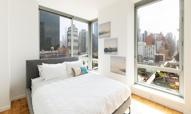 photo of 455 West 37th St Model Apartment 1017 view and corner bedroom staged with modern furniture - 455 W 37th St