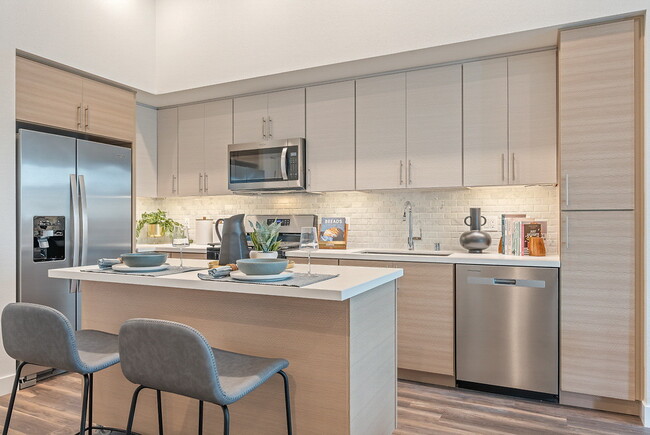 Imperial (2 BR, 2 BA). Kitchen with stainless steel appliances, island, and wood-style flooring. - LIVIA at Scripps Ranch