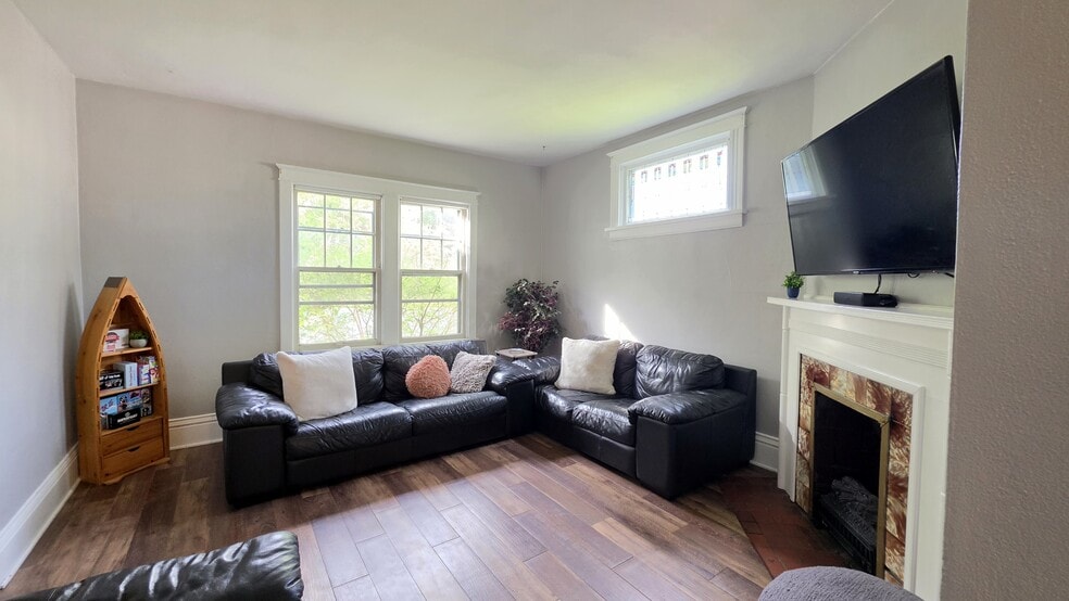 Bright, inviting living room with comfortable seating, electric fireplace, and 55" Smart TV. - 822 E 4th St