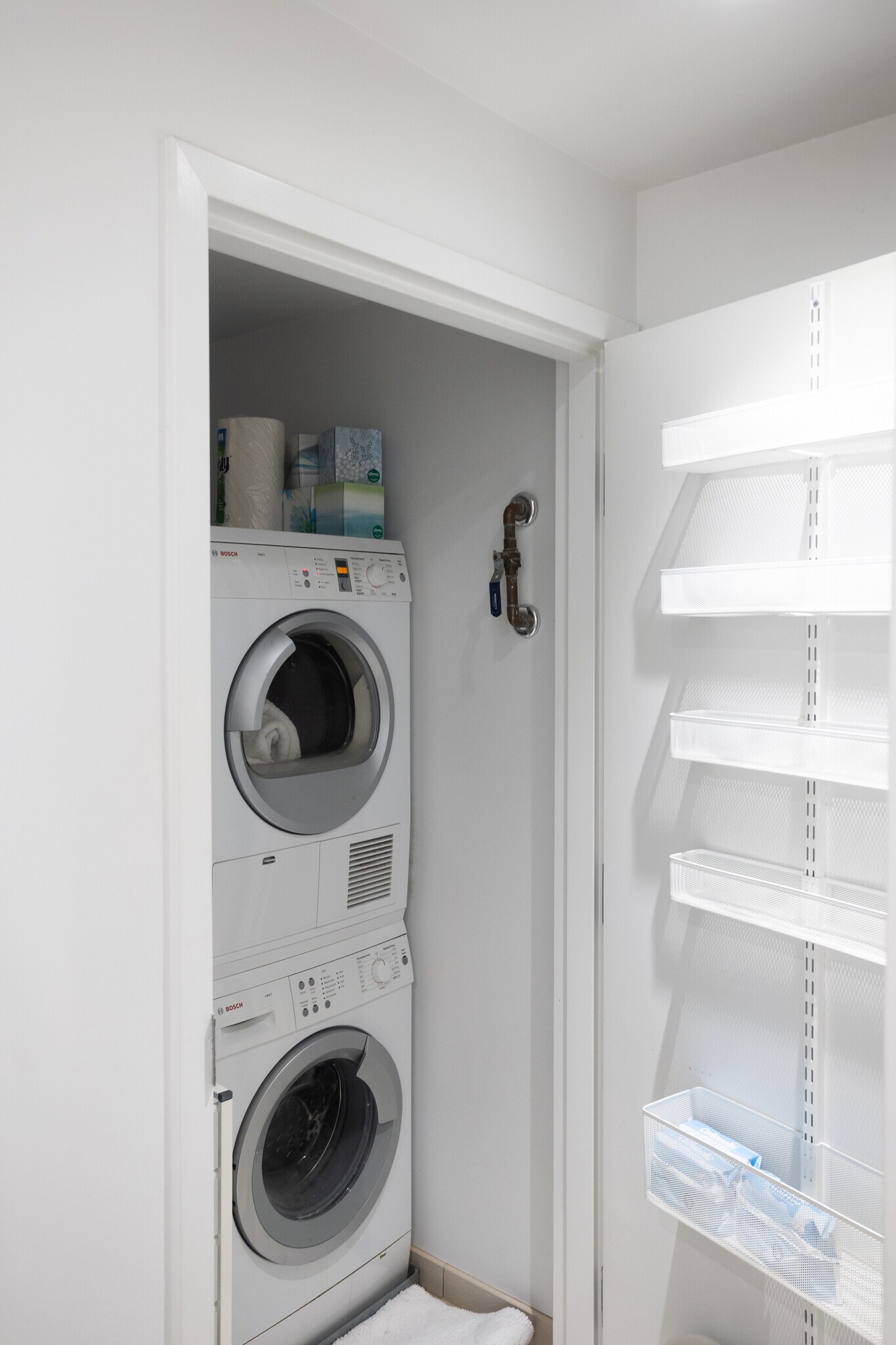 Stacked Bosch HE washer and dryer unit inside utility closet located in bathroom. - 2250 11th St NW