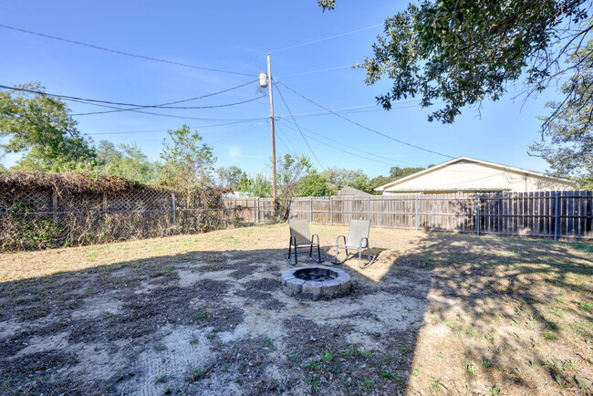 View of yard with privacy fence and an outdoor fire pit. - 209 Prairie Wind Blvd