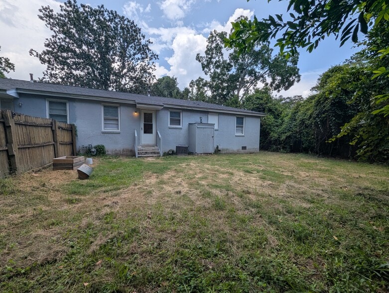 Rear exterior view of the home showing the expansive yard and surrounding mature shade trees. - 1527 Brookbank Ave