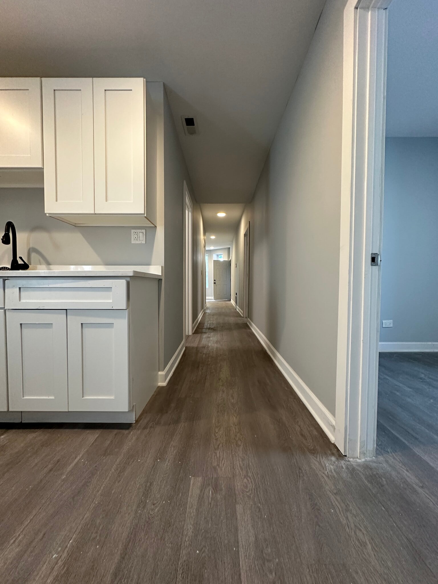 Renovated kitchen with white cabinetry and a view down the hallway - 5653 S May St