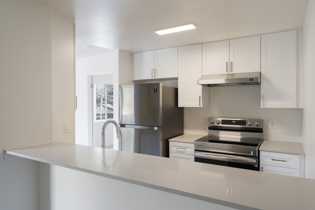 Renovated Package I kitchen with stainless steel appliances, light grey quartz countertops, and new white cabinetry - eaves Mission Viejo