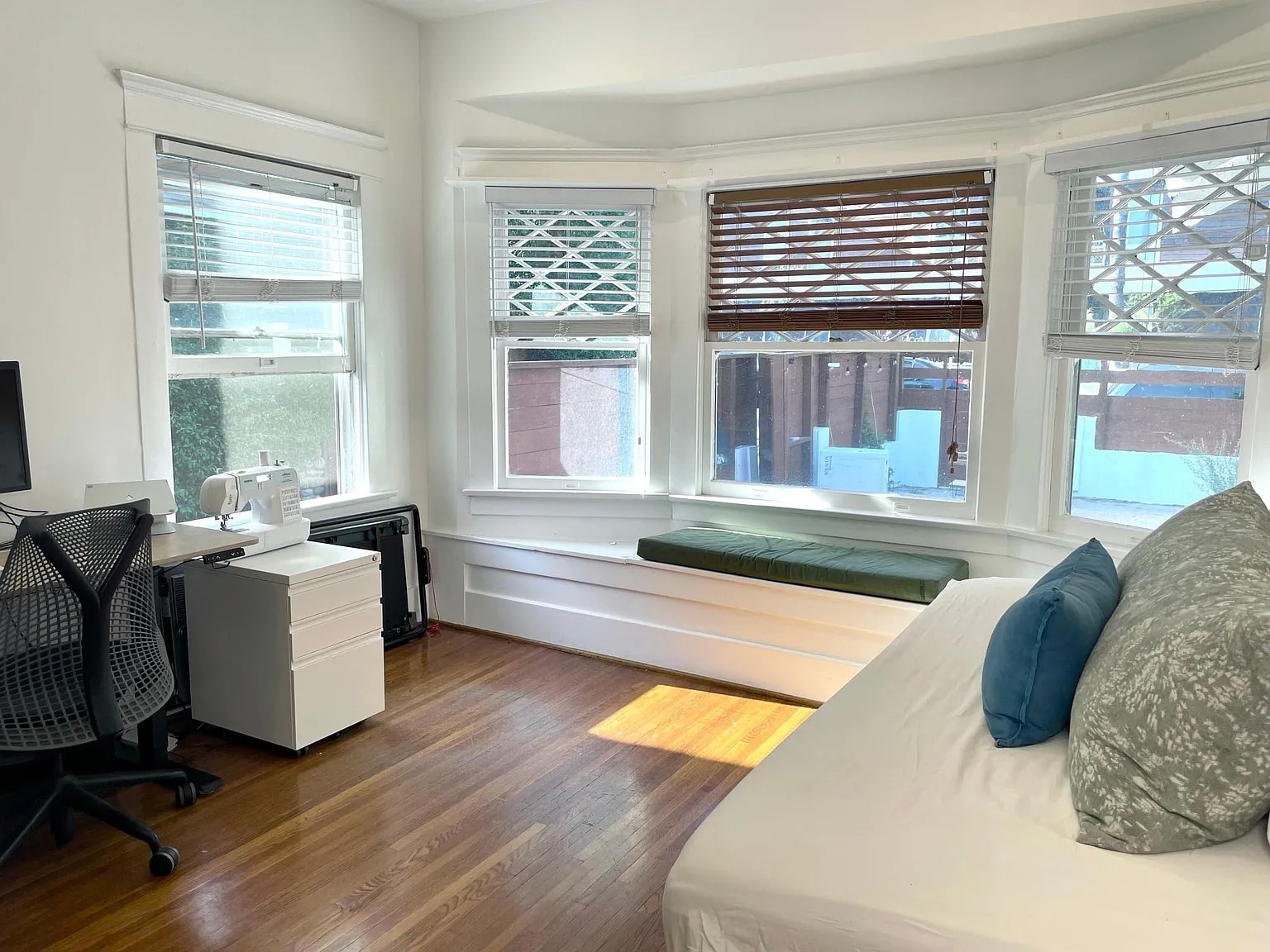 Bright second bedroom with bay windows, built-in window seat, and hardwood floors. - 6000 Carlton Way