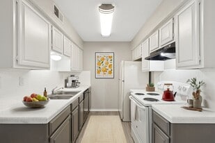 A chef's kitchen is shown with white and black appliances, red tea kettle on stove, and bowl of fruit on the counter. - ReNew Holiday Hill®