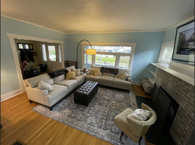 The living room offers a cozy, comfortable space with two large couches and a TV, perfect for unwind - 3012 N 22nd St