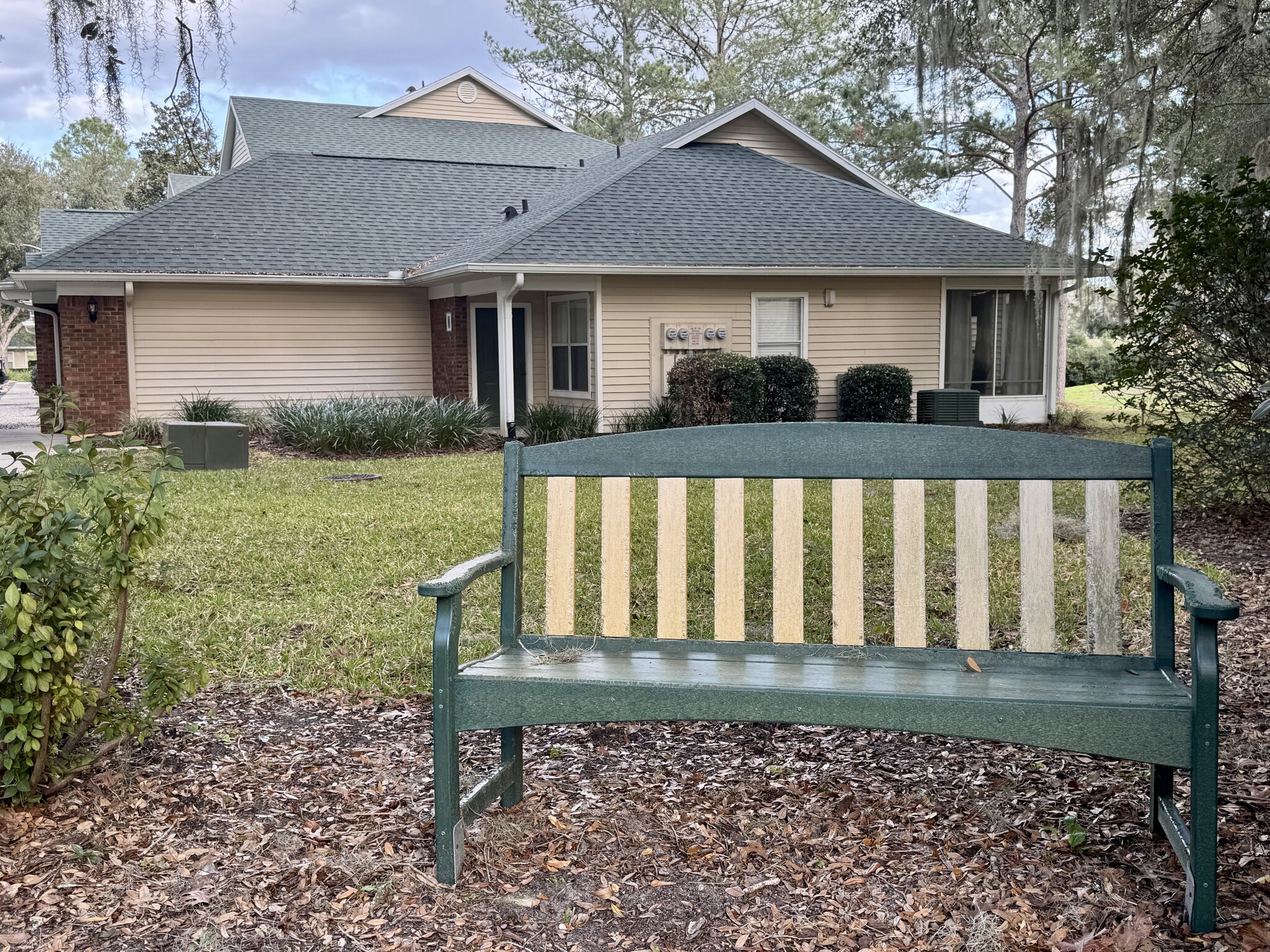 Green space bench nestled between pink Azalea bushes - 13200 W Newberry Rd