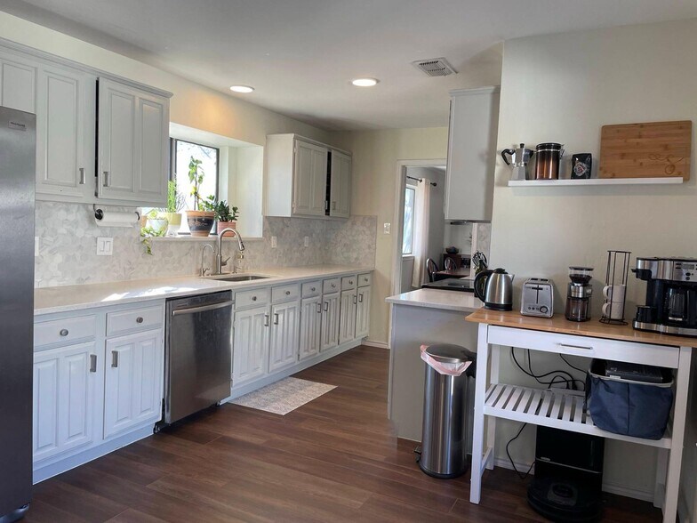 Extended view of the spacious kitchen with coffee station, bar seating, and bright light. - 2401 Thistle Ct