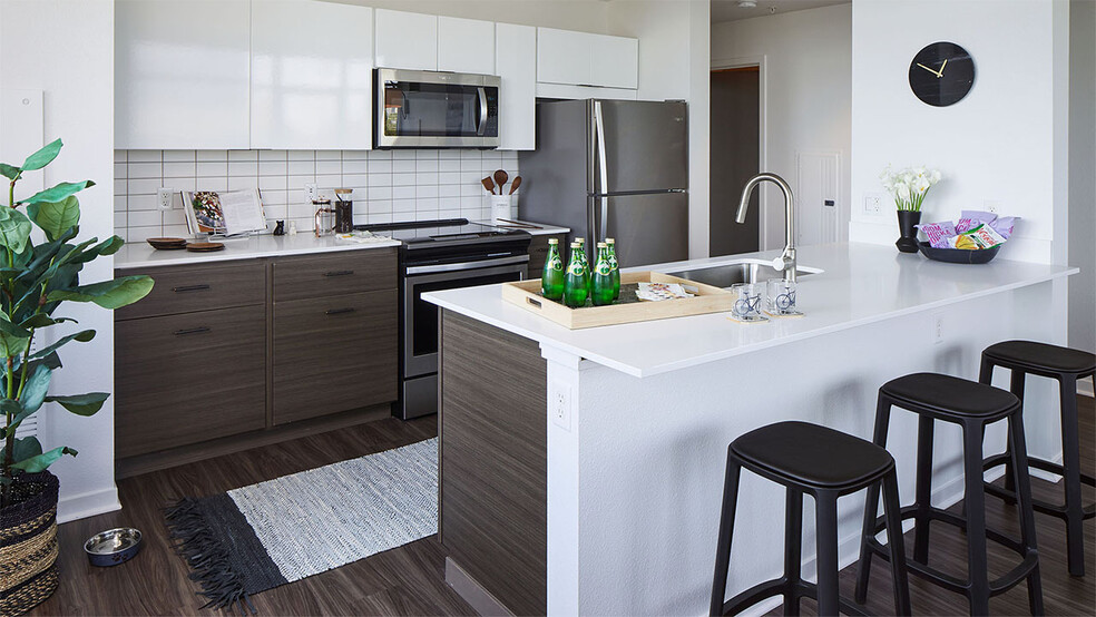 Apartment Kitchen with Stainless Steel Appliances, quartz counters and wood floors. - Griffis South Waterfront