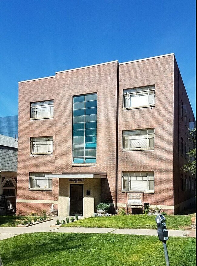 Elegant brick apartment building with large windows and a well-maintained lawn. - Hillside Apartments
