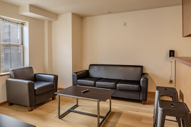 Relax in this charming living room, perfect for unwinding and entertaining. - Varsity Campus Apartments