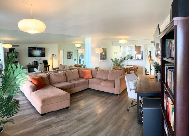 Living room with large couch, desk, TV; next to dining area with dinner table - 4337 Marina City Dr