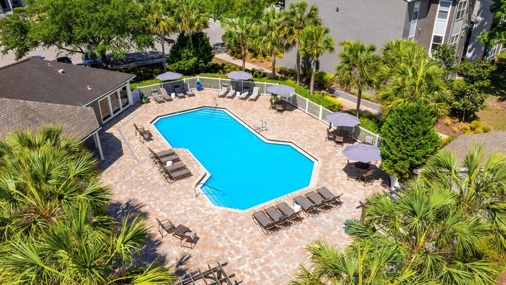 A stunning aerial look at The Enclave at Huntington Woods' sparkling swimming pool—complete with spacious sundeck, lounge chairs, and shaded seating for the perfect day under the Florida sun. - The Enclave at Huntington Woods