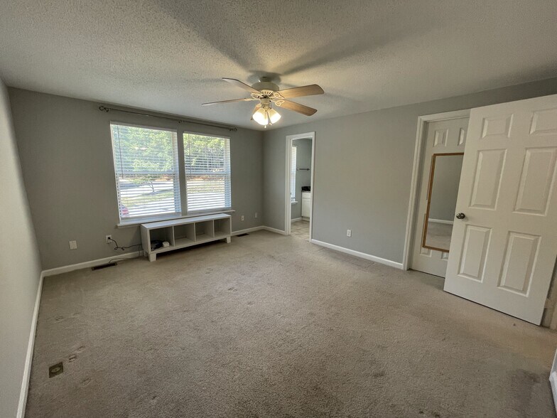 Main bedroom with en suite bathroom, custom under-window storage, ceiling fan, and walk-in closet - 4204 Whistler Ct