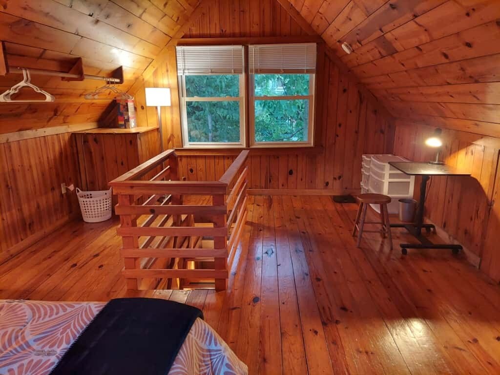 Upstairs, view from bed: small desk and stool, bath scales and storage, lamp, clothes rod, basket - 311 Newton Aly