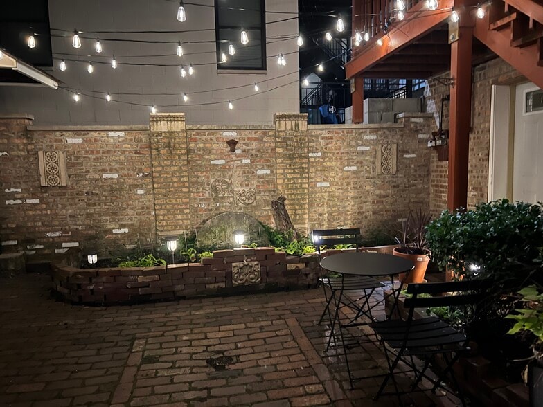 Canopy-lit courtyard separating front house and coach house by night - 2446 W Thomas St