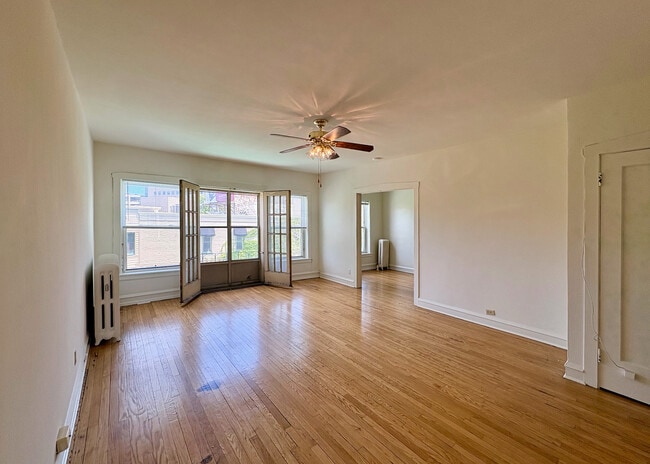 Inviting living room with elegant hardwood floors, ample natural light, and charming French doors. Perfect for relaxation and entertaining. - Ivanhoe
