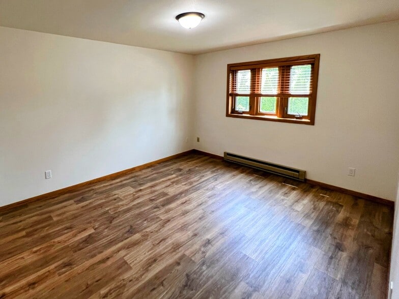 primary bedroom with wood-style floors, large window, and plenty of space for a queen or king bed - 213 Ash Street