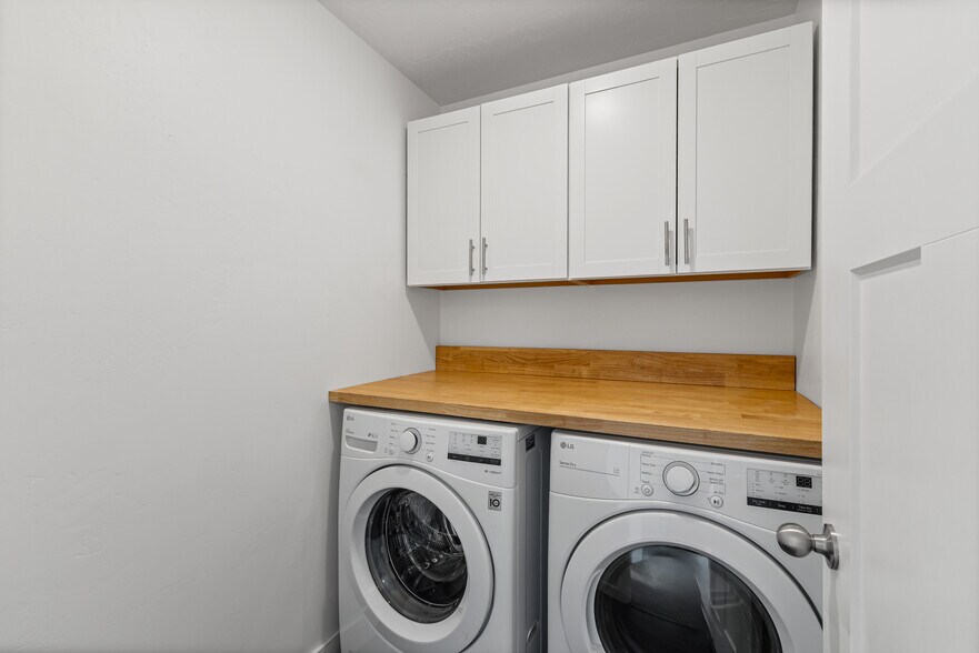 Laundry room with washer/dryer upper storage cabinets and butcher block table top - 4877 E Silver Ridge Rd