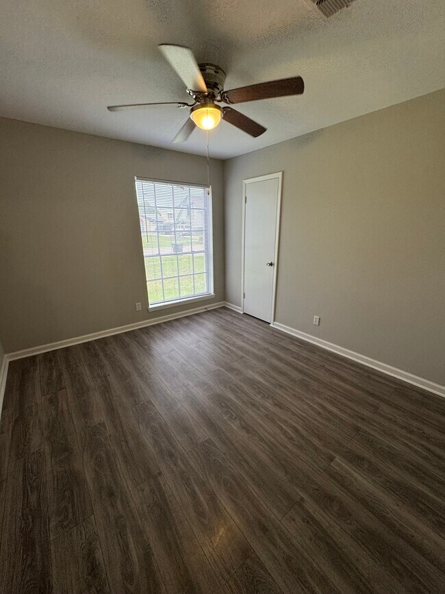 Front-facing bedroom with tons of natural light and a ceiling fan for comfort. - 11927 Troulon Dr