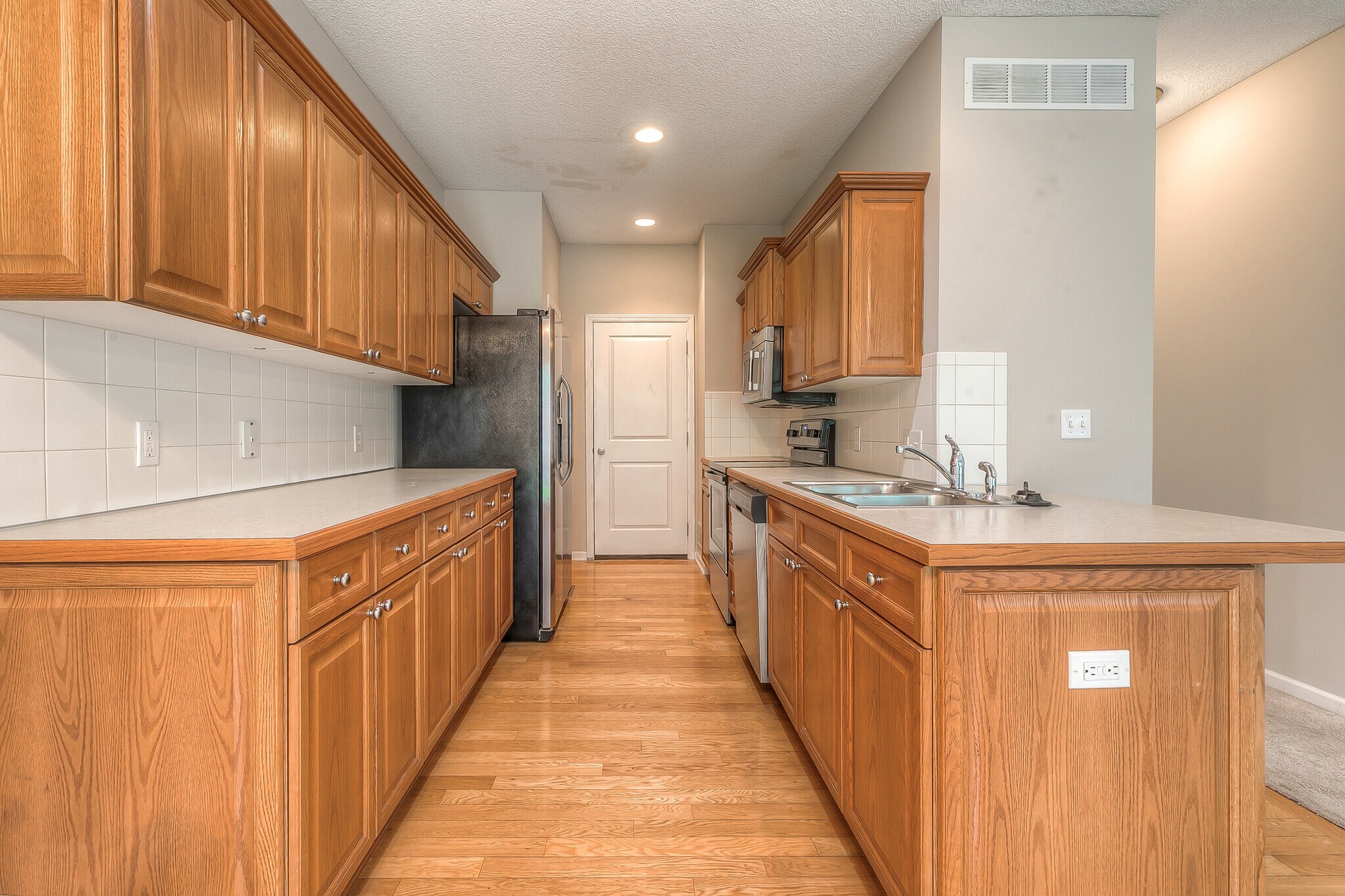 kitchen with hardwood floors, lots of cabinets and counter space. Pantry and door to garage, easy to bring in groceries. - 22810 West 71st Terrace