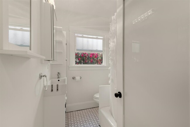 Beautiful white bathroom with storage conscious cabinets. Full bathroom with shower. - 2108 E 23rd St