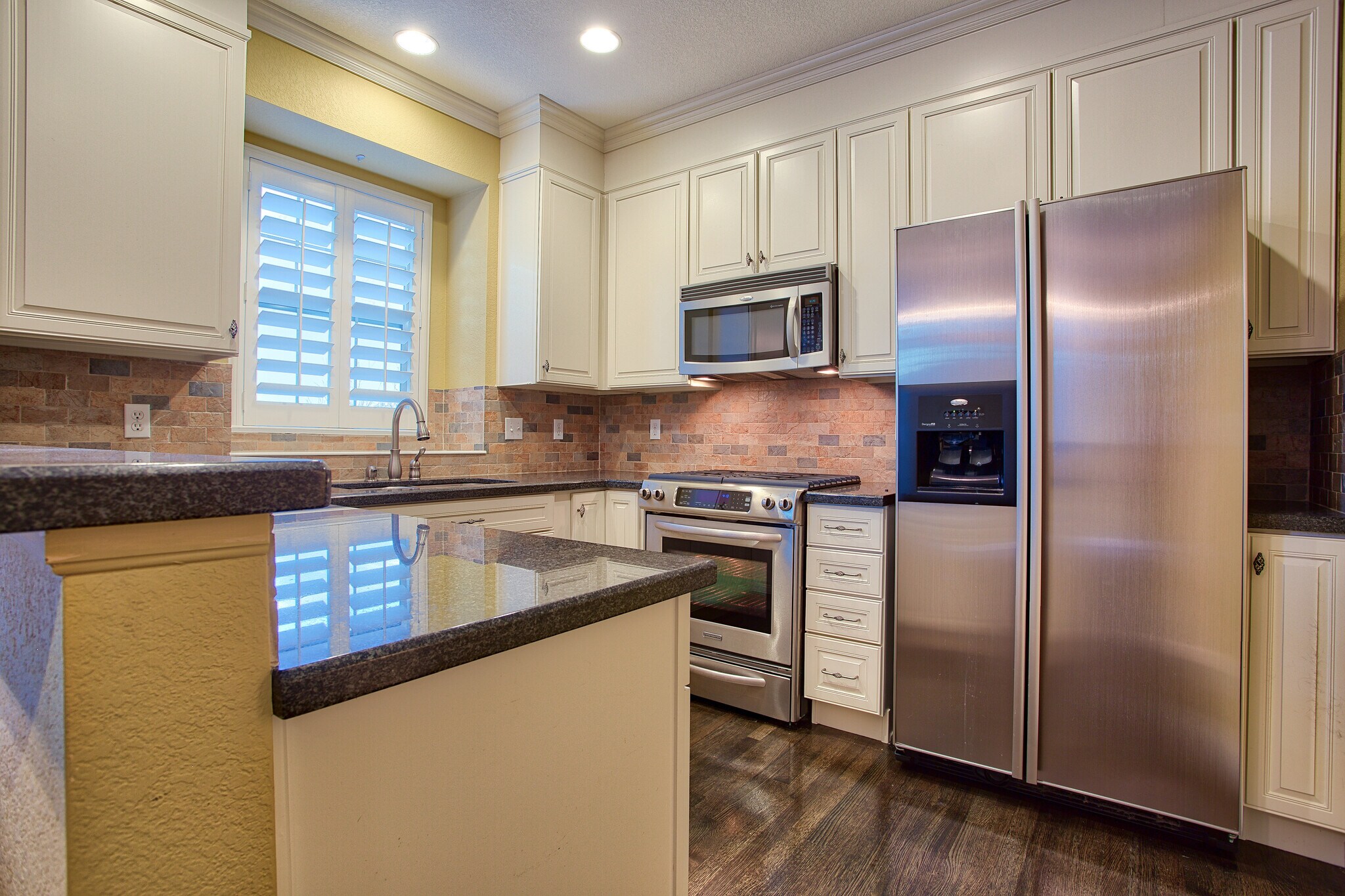 Kitchen with slab granite counters, gas stove, microwave, dishwasher, stainless appliances - 7422 E 7th Ave Unit 14