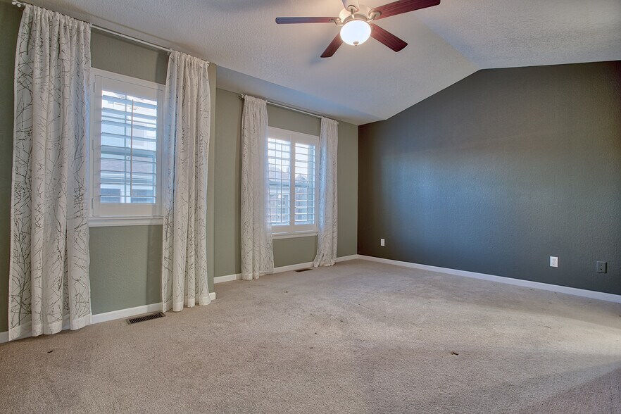 Master bedroom with vaulted ceiling, ceiling fan, and plantation shutters - 7422 E 7th Ave Unit 14