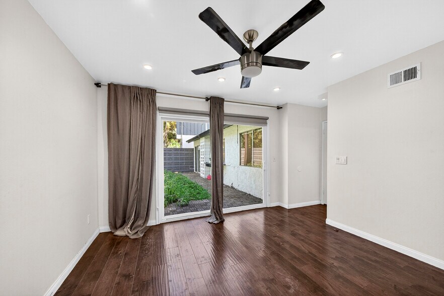 Dark wood flooring and clean natural walls create a warm, modern canvas in the primary suite. - 5214 Dawes Ave