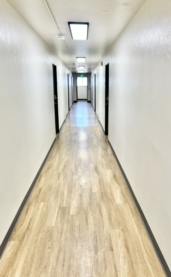 Bright and spacious hallway with modern lighting and sleek wood flooring. - Rhapsody Apartments