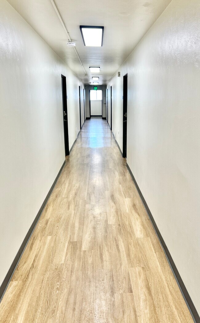 Bright and spacious hallway with modern lighting and sleek wood flooring. - The Sloan