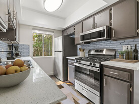 Tiled kitchen with stainless steel oven, microwave, and fridge. - Sherman Oaks Gardens