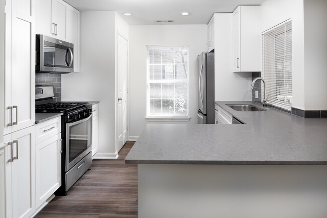 Kitchen with gray quartz countertops, tile backsplash, stainless steel appliances, and upgraded fixtures - Avalon at Bedford Center