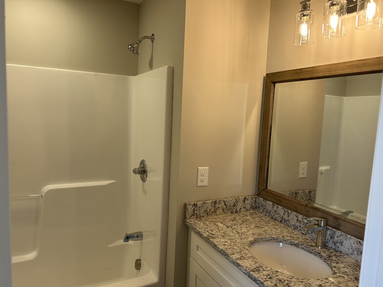 private bath for bedroom #1, granite countertops, tub/shower, framed mirred and craftsman cabinets - 334 Bailey St