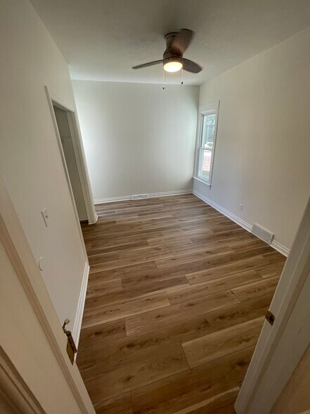 The master bedroom with a window in the corner that has views of the lake and a fan - 1219 State St
